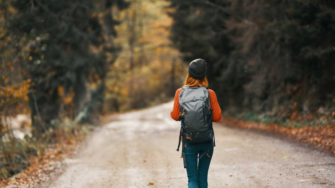 Frau mit Rucksack wandert durch einen Wald